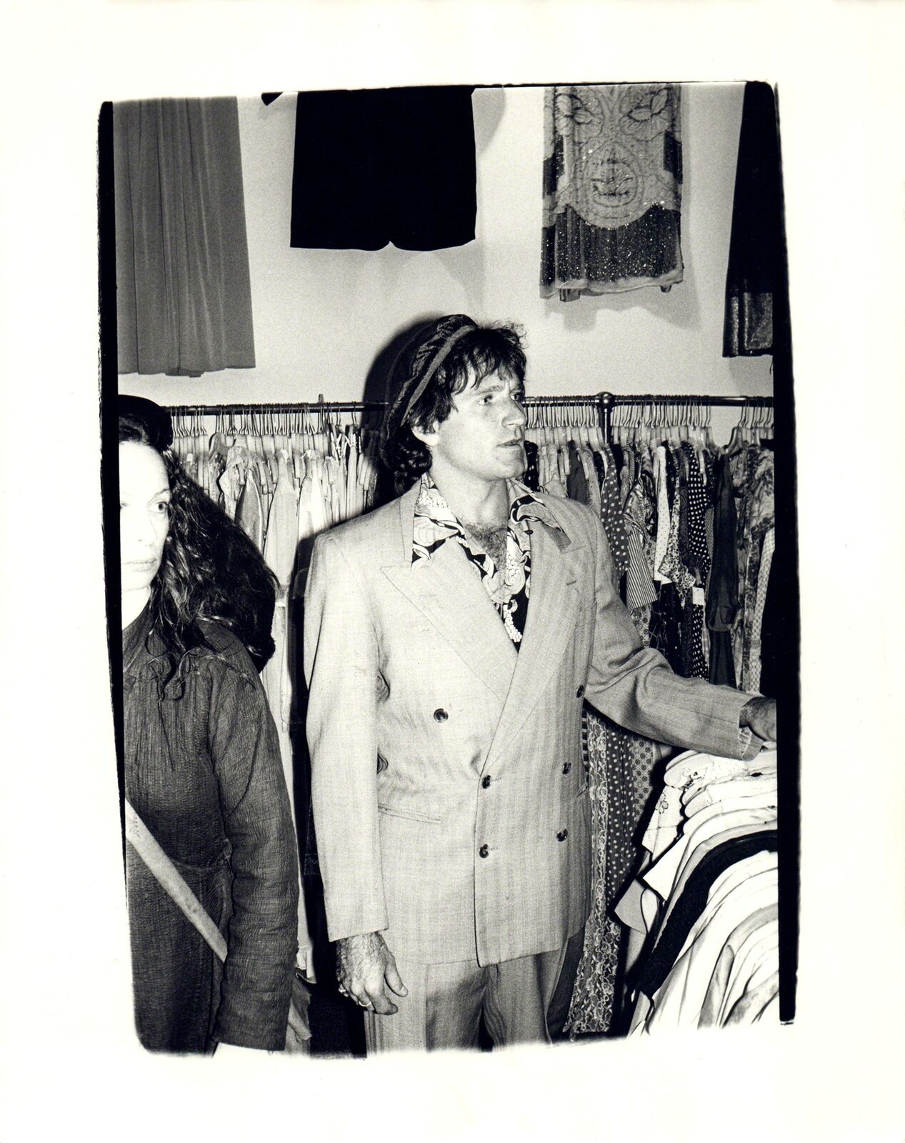 A man in a suit standing next to a woman in a closet.