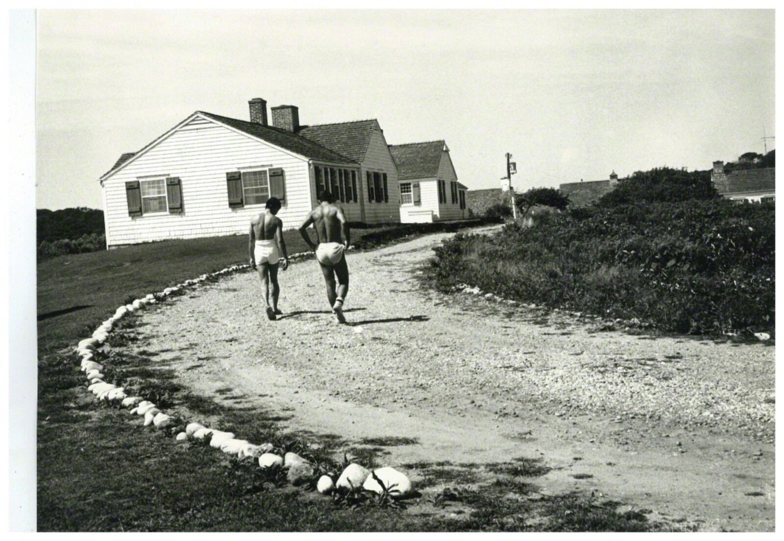 A couple of people walking down a dirt road.
