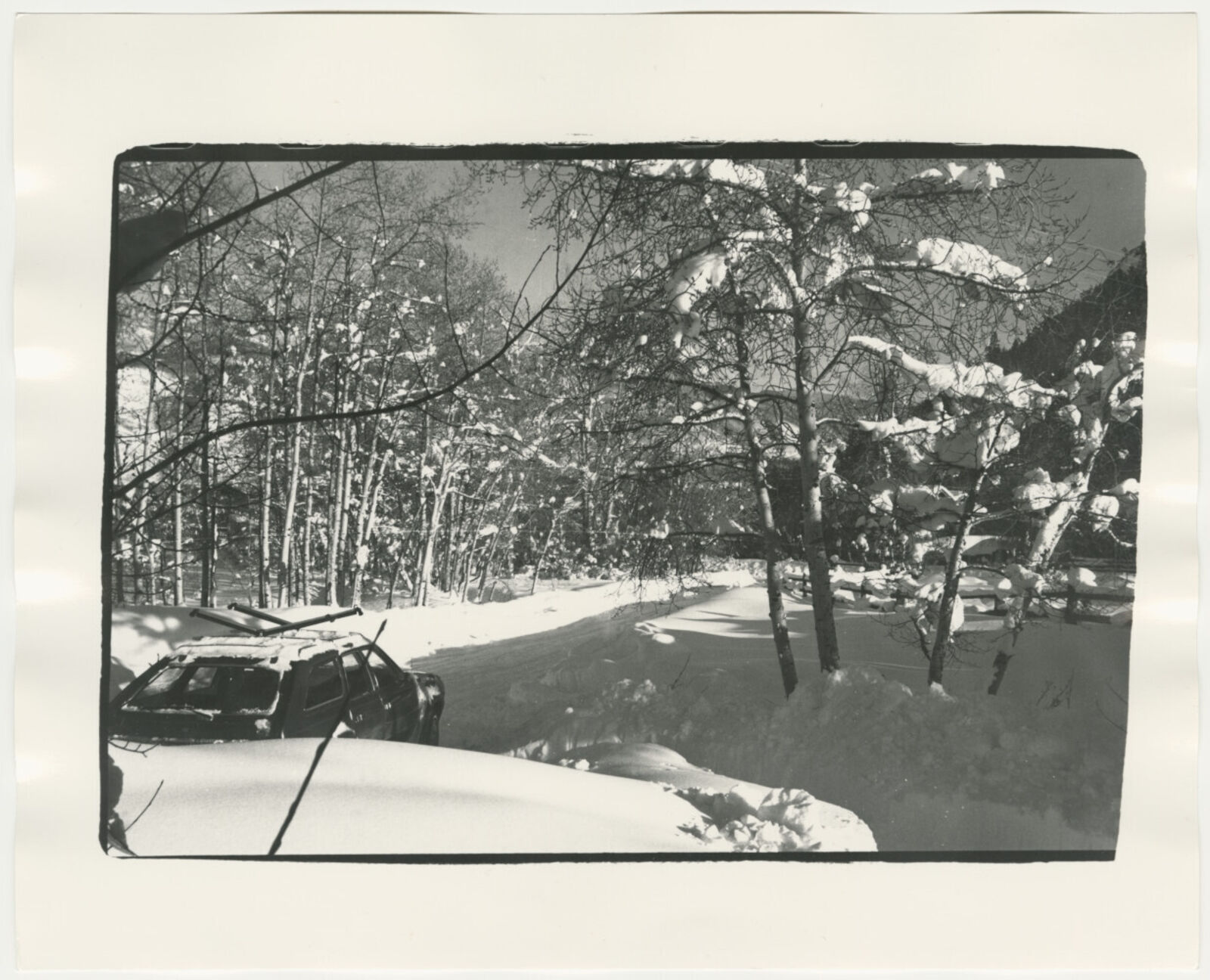 A black and white photo of a car parked in the snow.