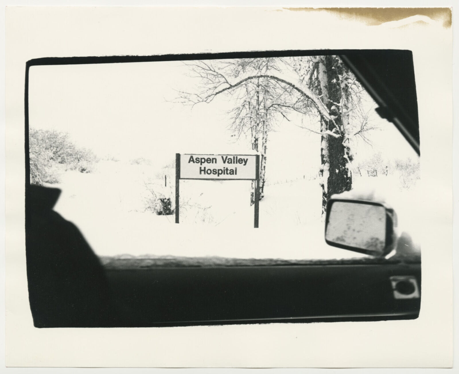 A black and white photo of a hospital sign in the snow.