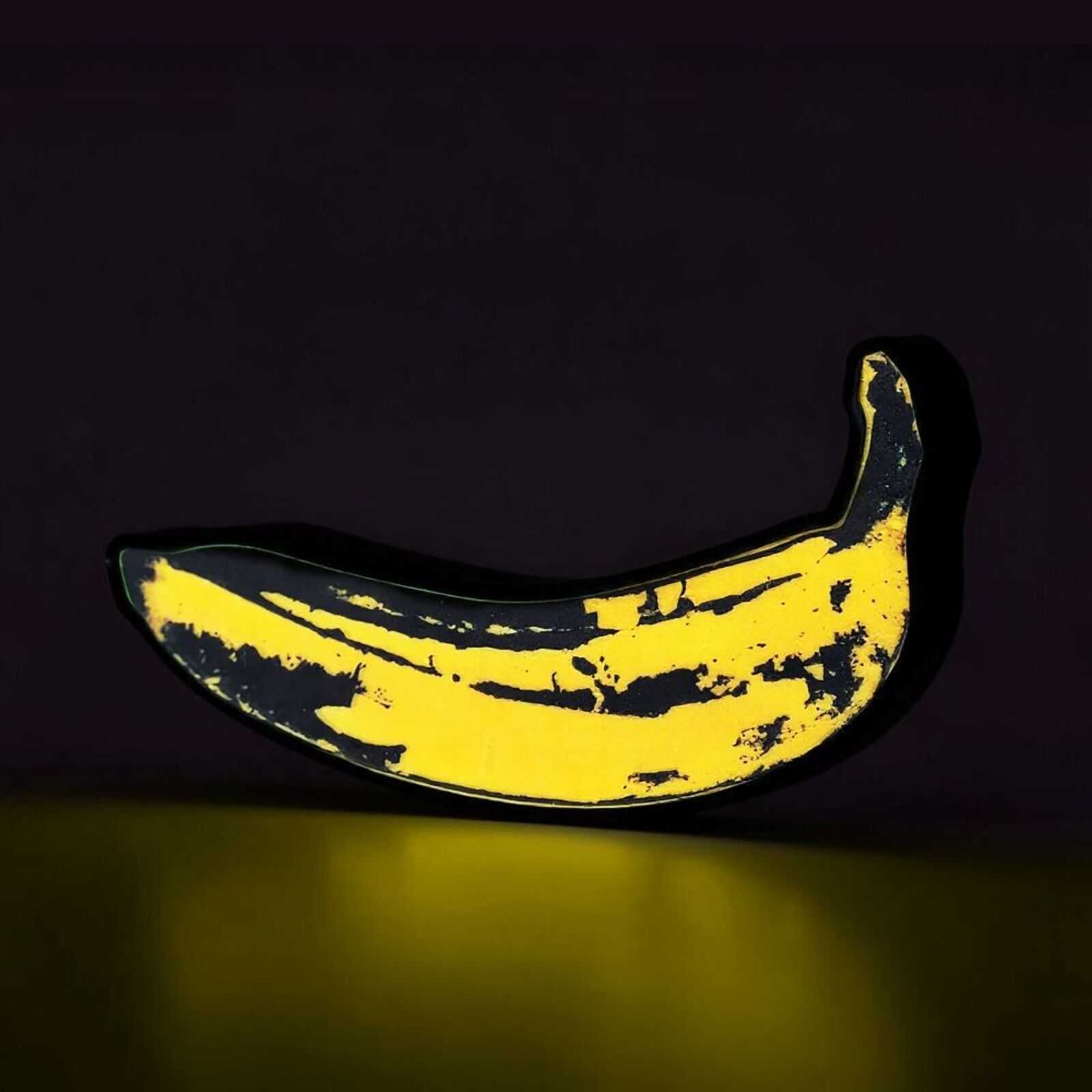 A yellow and black banana shaped object on a white surface.