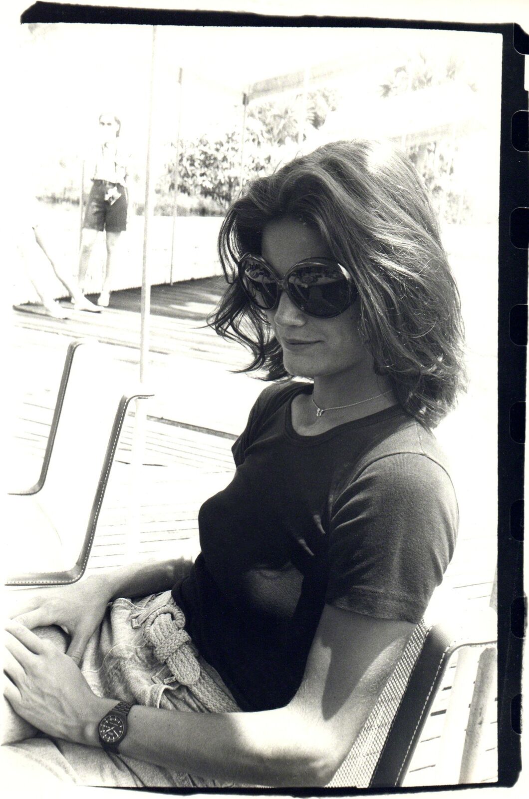A black and white photo of a woman sitting on a bench.