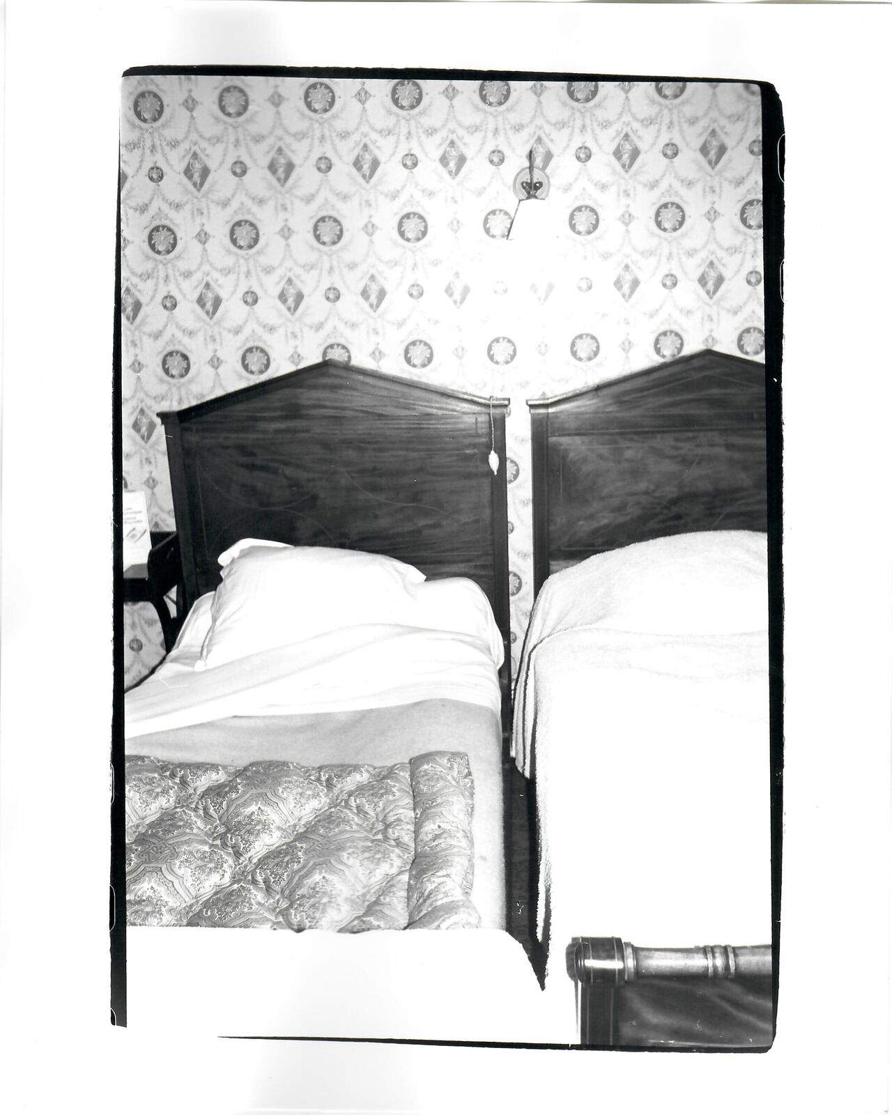A black and white photo of two beds in a room.