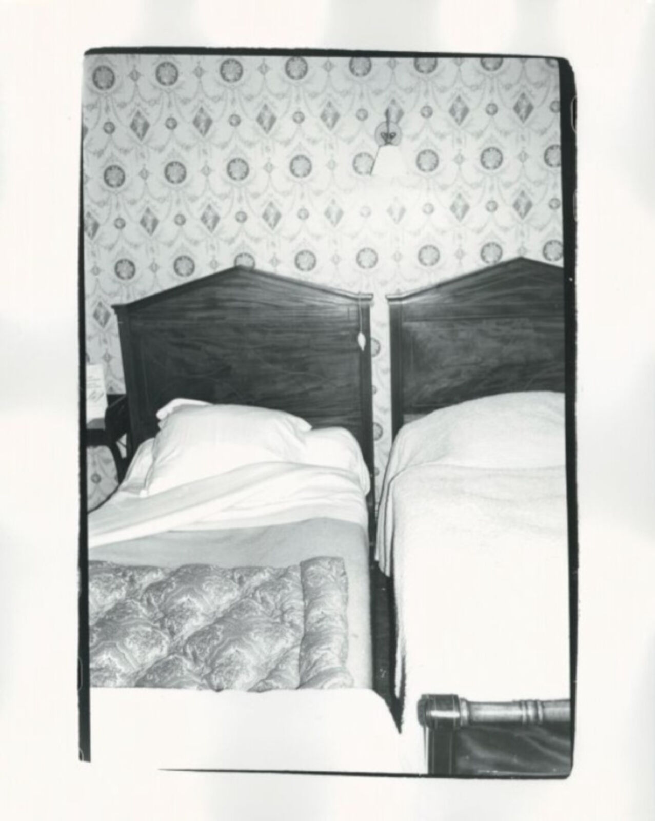 A black and white photo of two beds in a room.