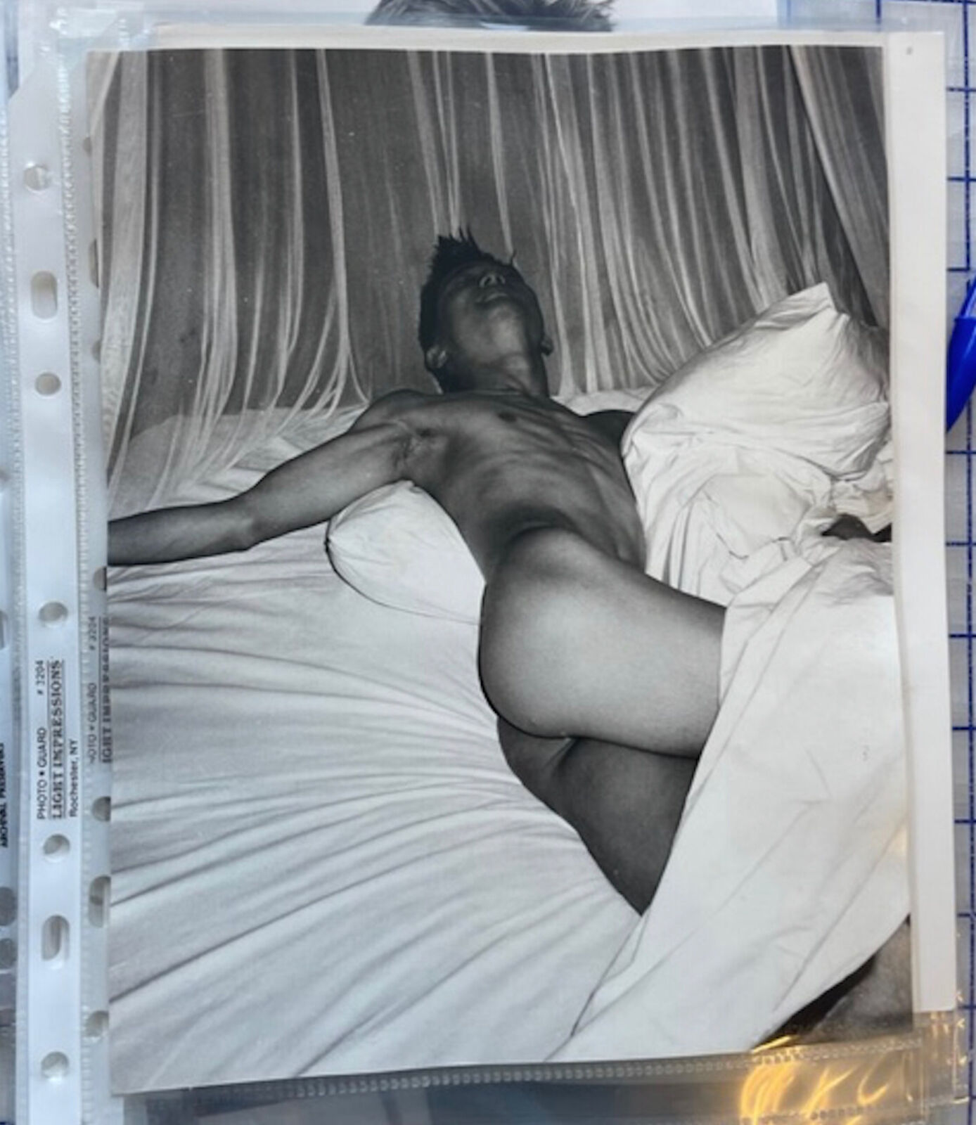 A naked man laying on a bed with white sheets.