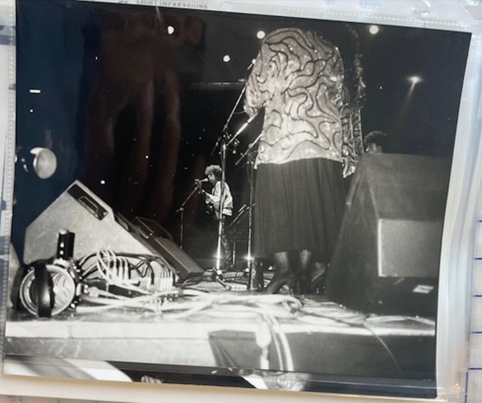 A black and white photo of a woman standing on a stage.