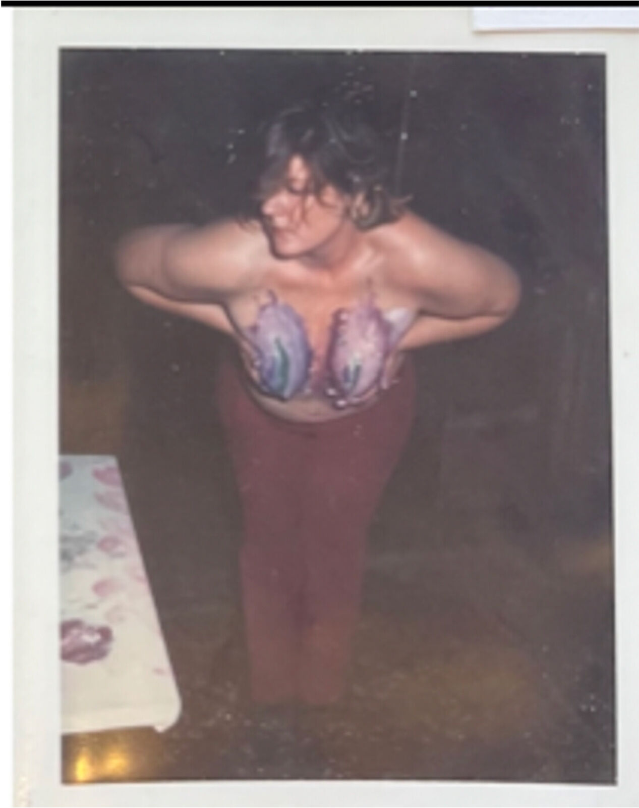 A woman standing in a room with her hands on her breasts.