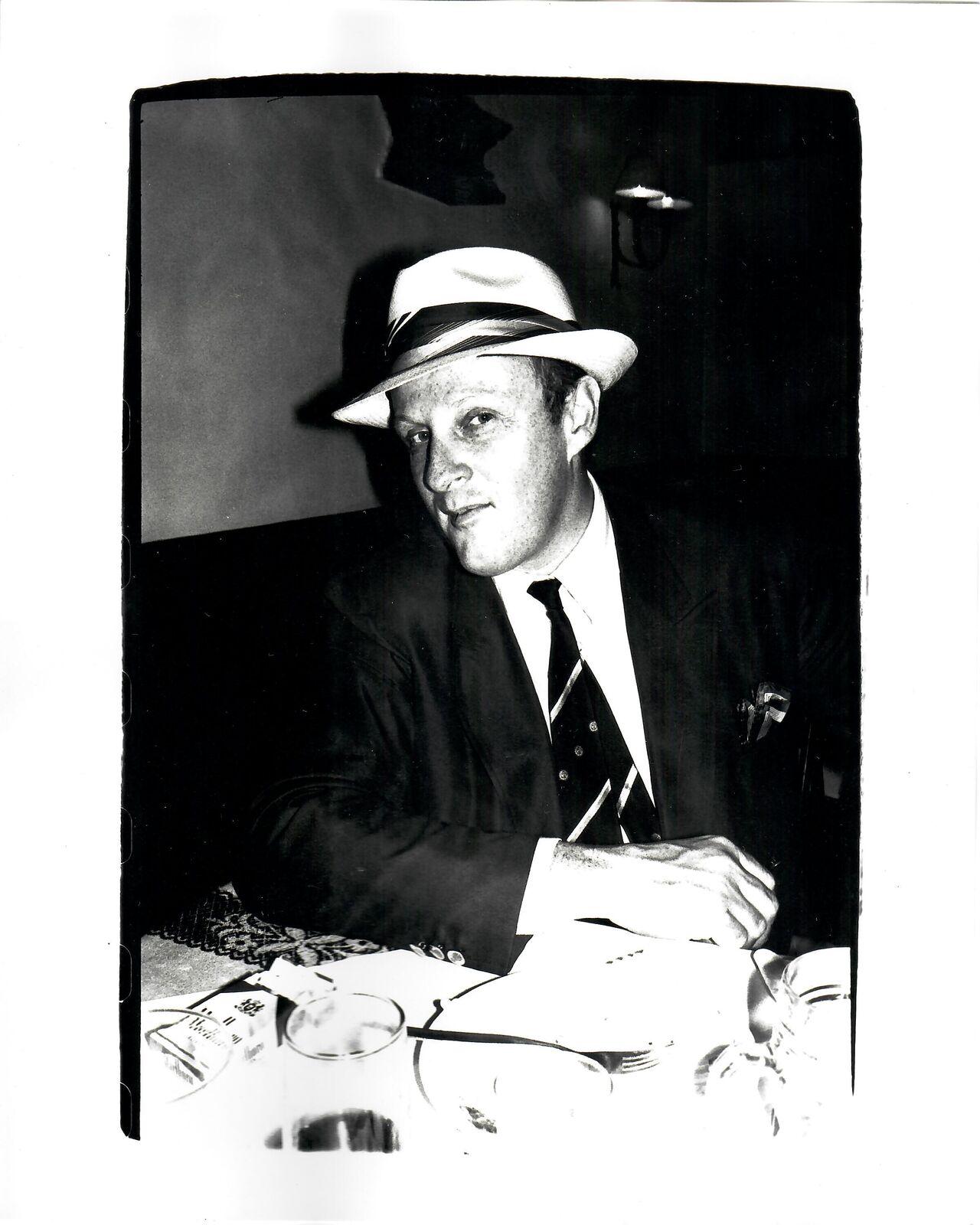 A black and white photo of a man in a suit and hat.