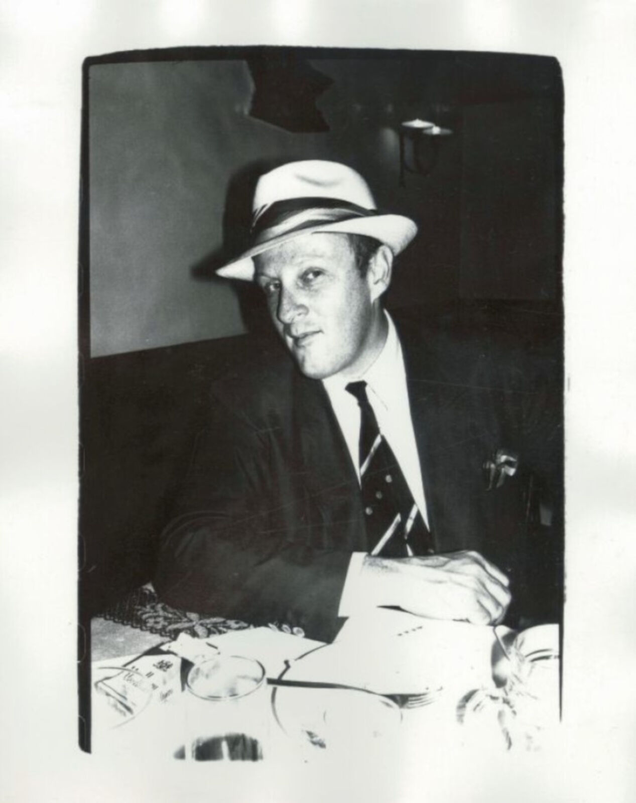 A black and white photo of a man in a suit and hat.