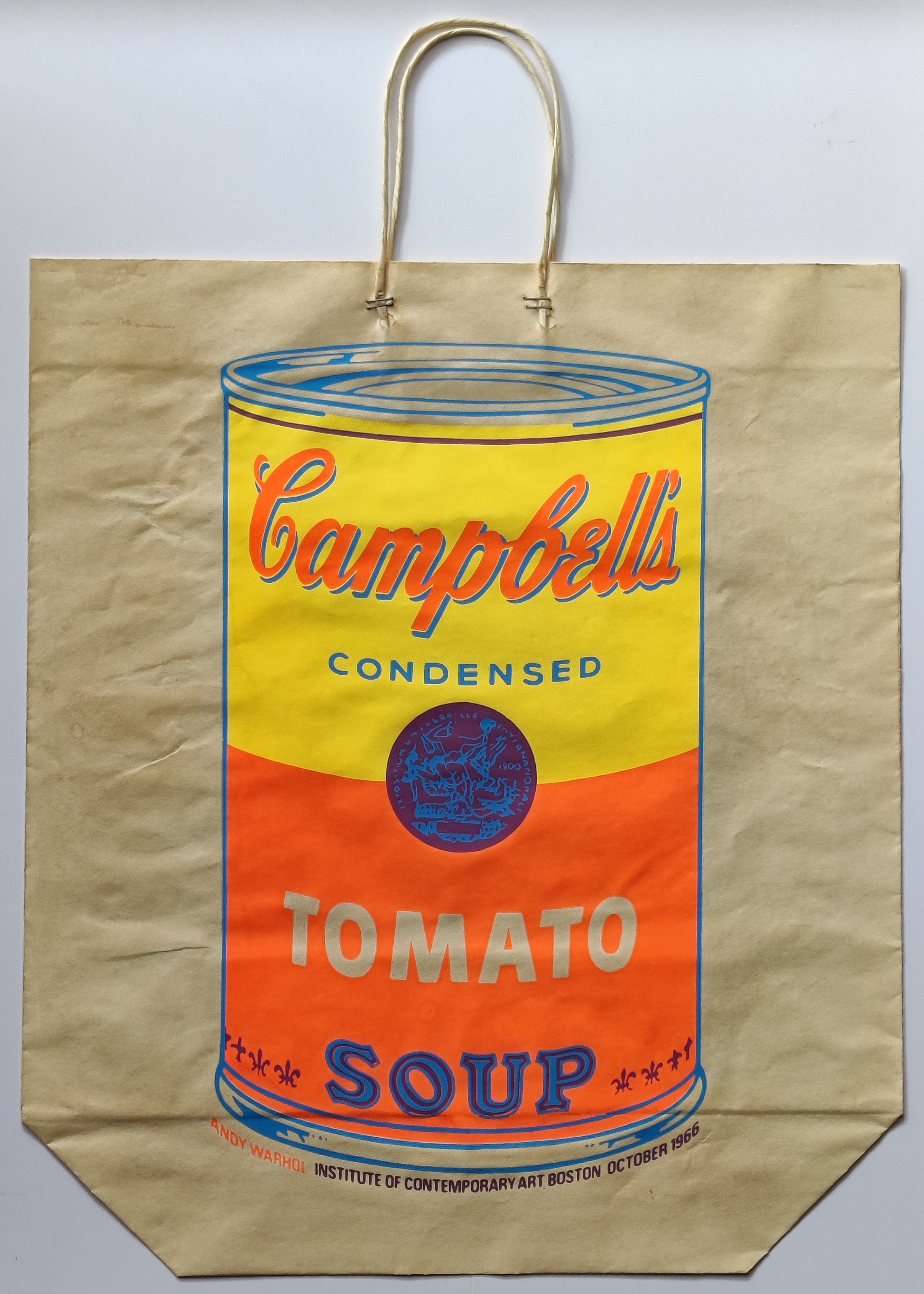 A paper bag printed with a stylized soup can design featuring bold colors and retro typography.