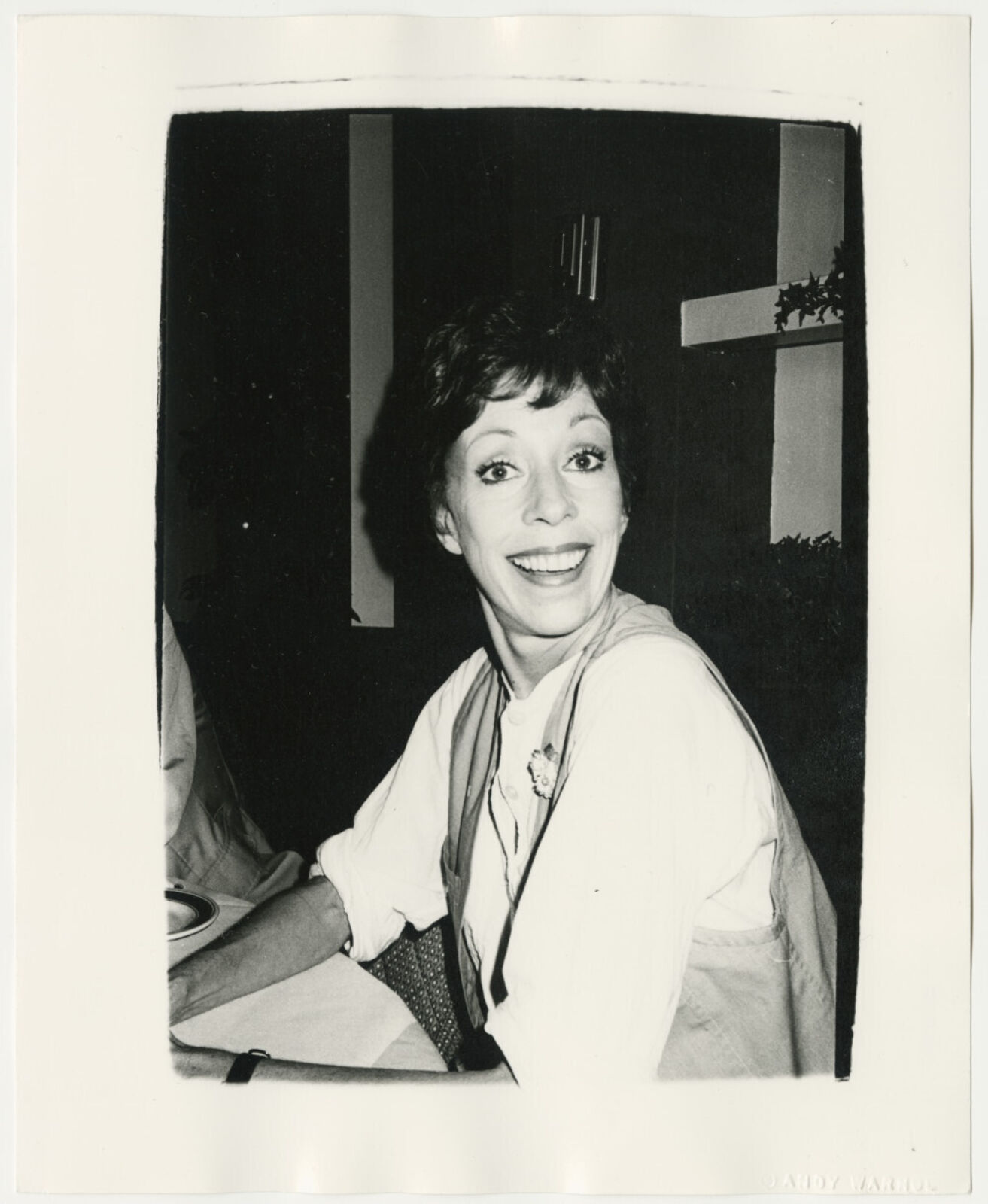 A black and white photo of a woman smiling at the camera.
