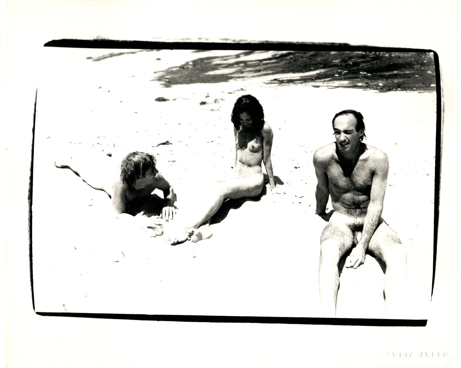 A black and white photo of three people on the beach.