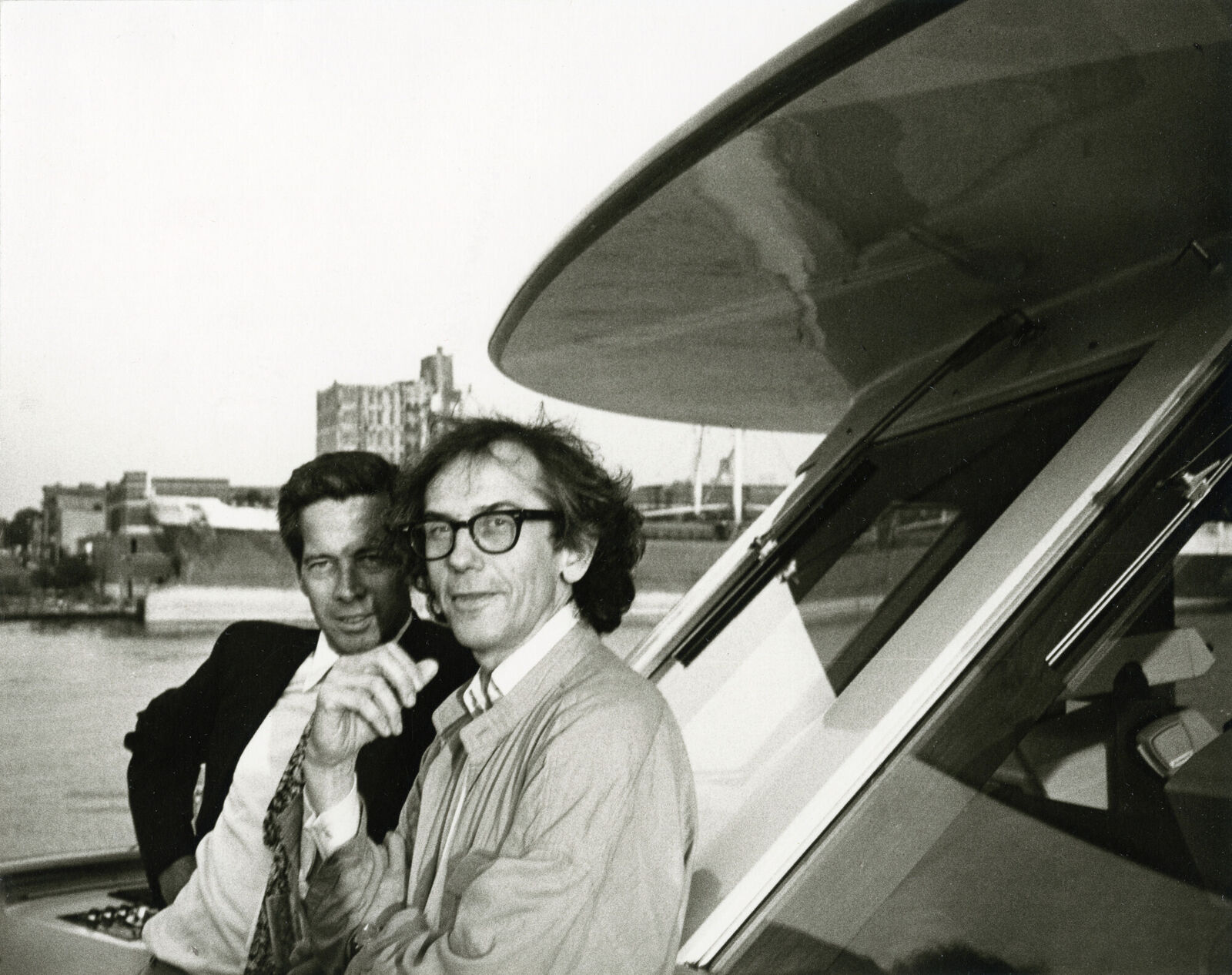 Two men sitting on the back of a boat on the water.