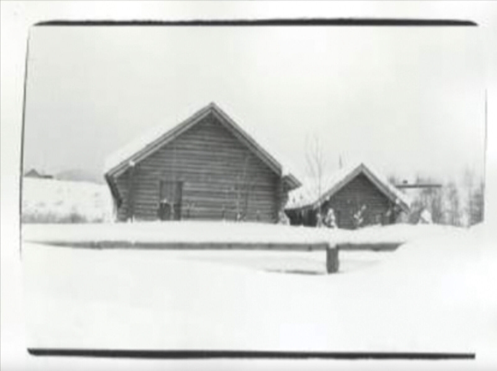 A black and white photo of a house in the snow.