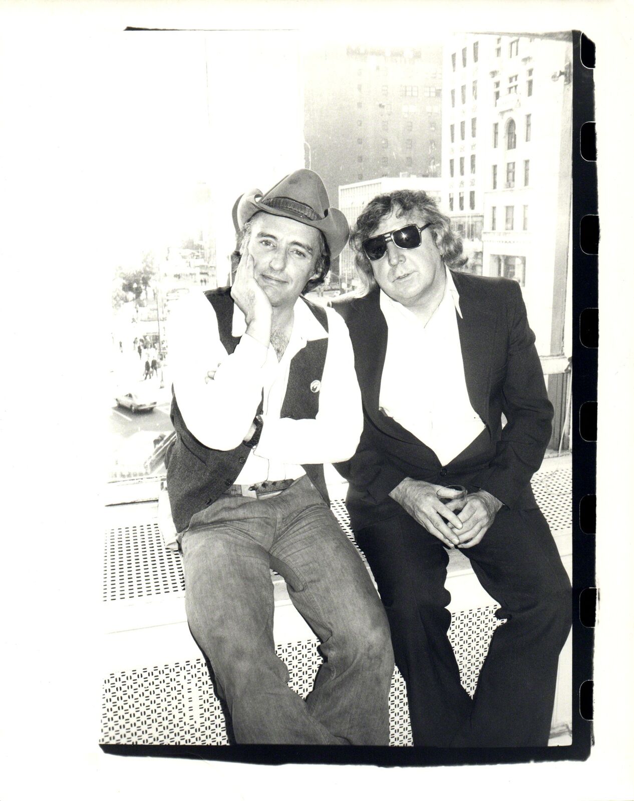 A black and white photo of two men sitting next to each other.