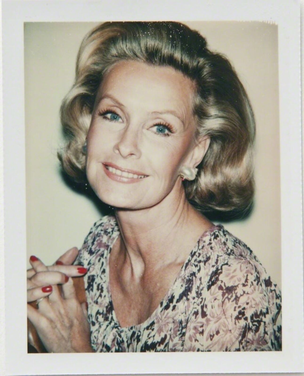A polaroid photo of a woman with blonde hair and blue eyes.
