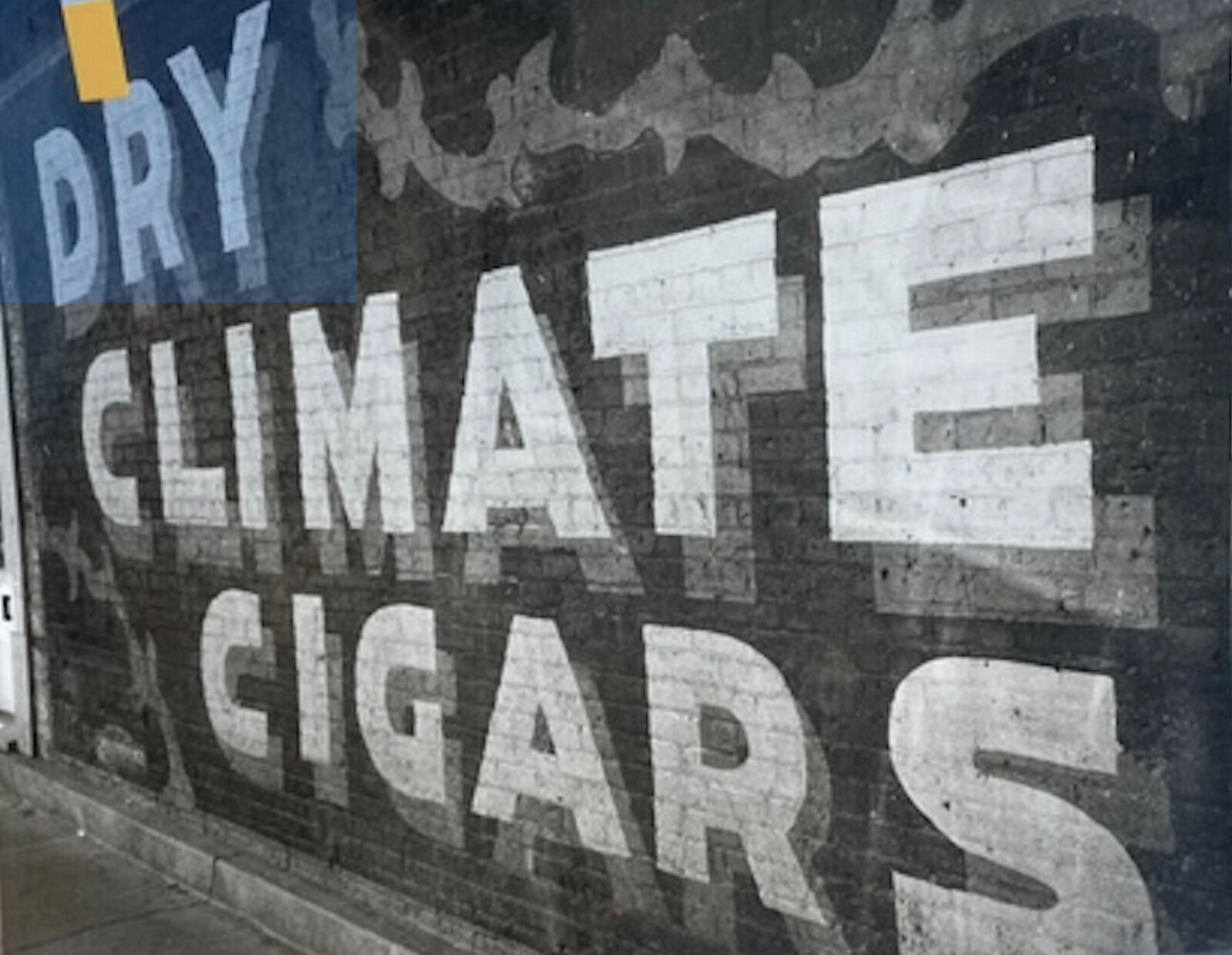 A sign on the side of a building that says Dry Climate Cigars.