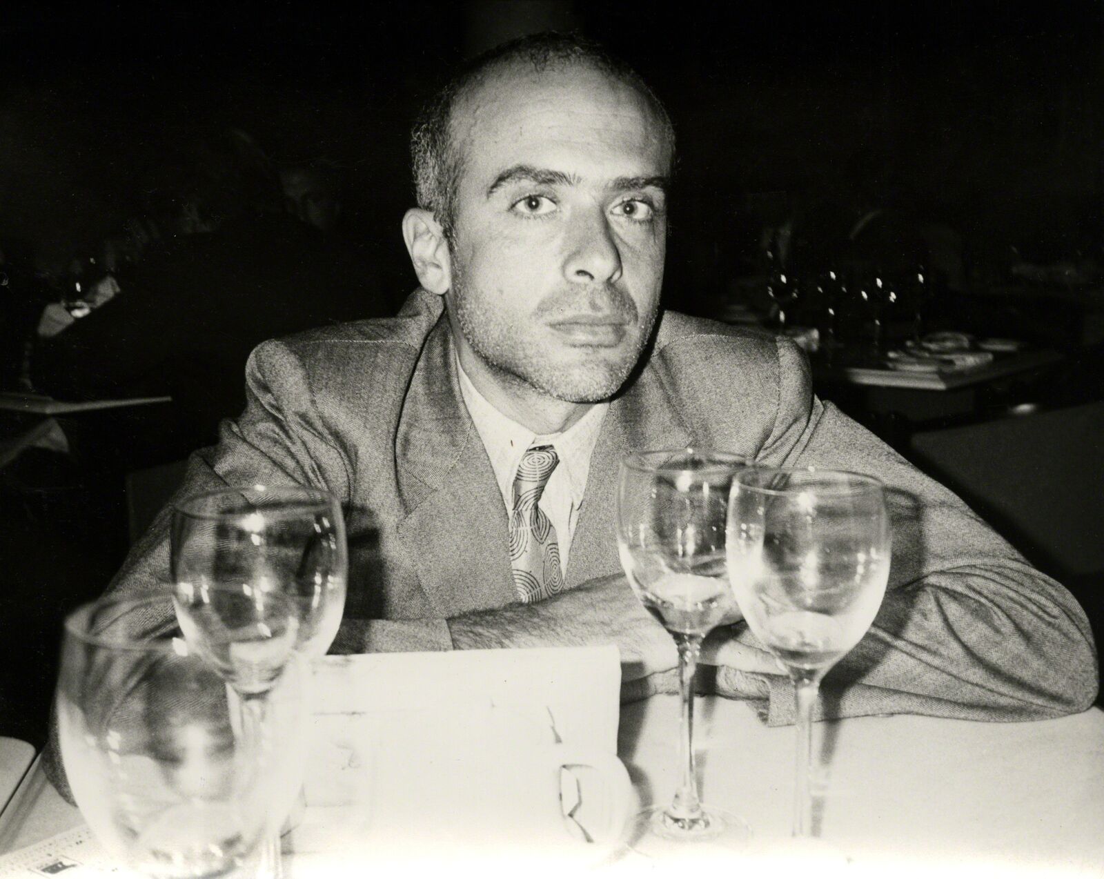 A man sitting at a table with wine glasses.