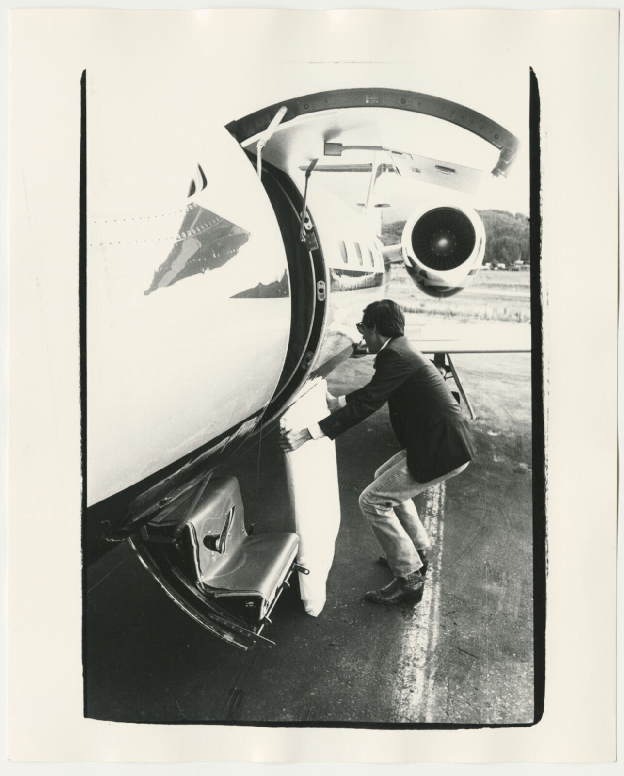 A black and white photo of a man getting off of an airplane.