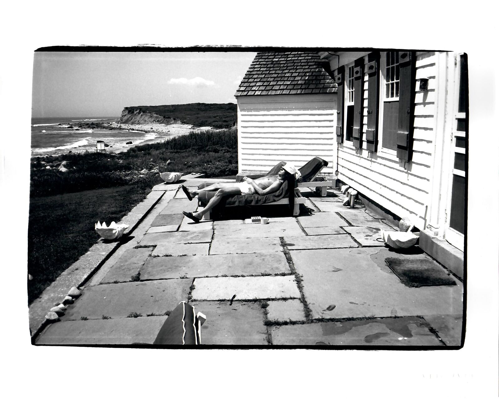A black and white photo of a person laying on a lawn chair.