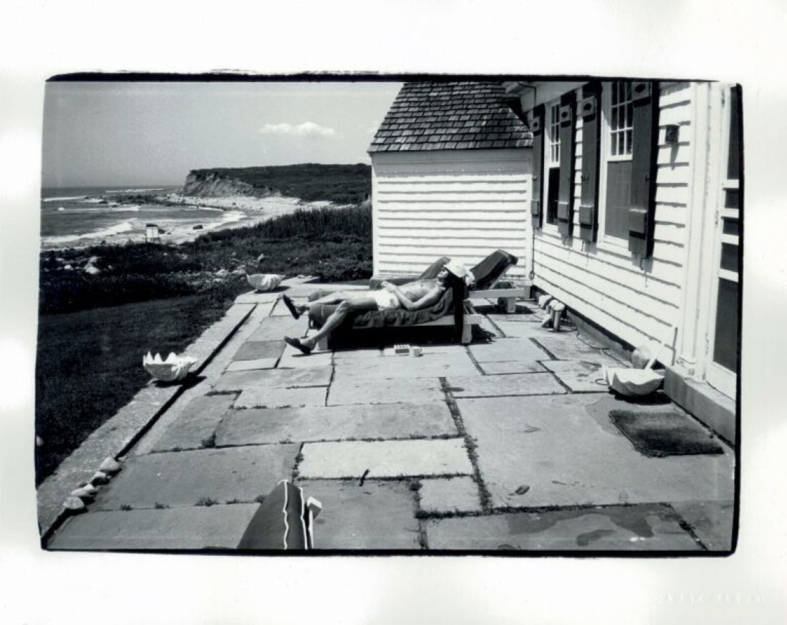 A black and white photo of a person laying on a lawn chair.