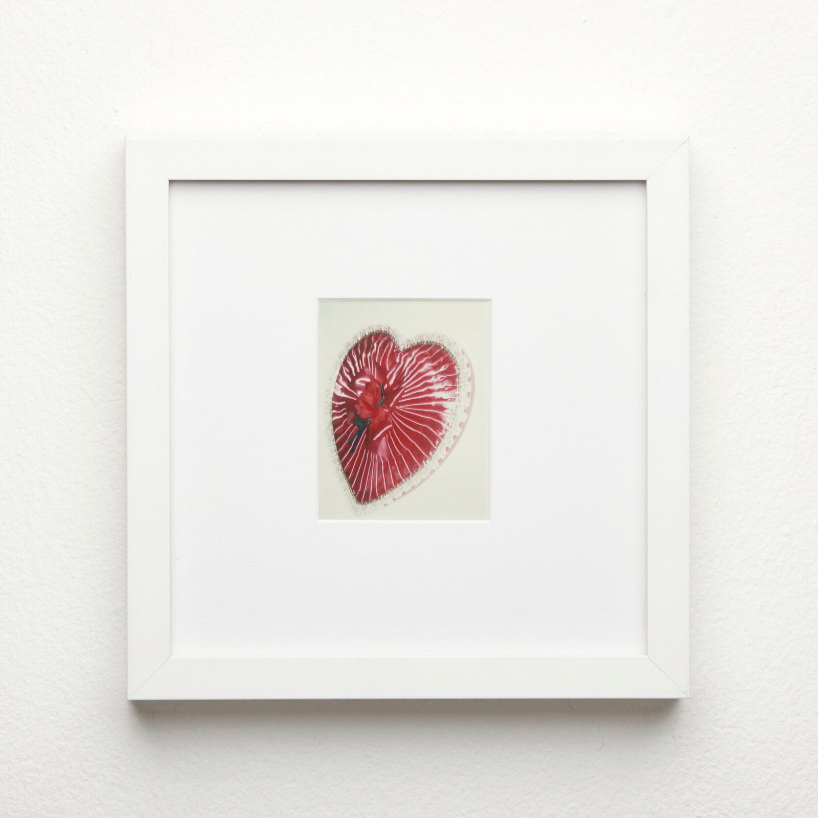 A picture of a red heart in a white frame.