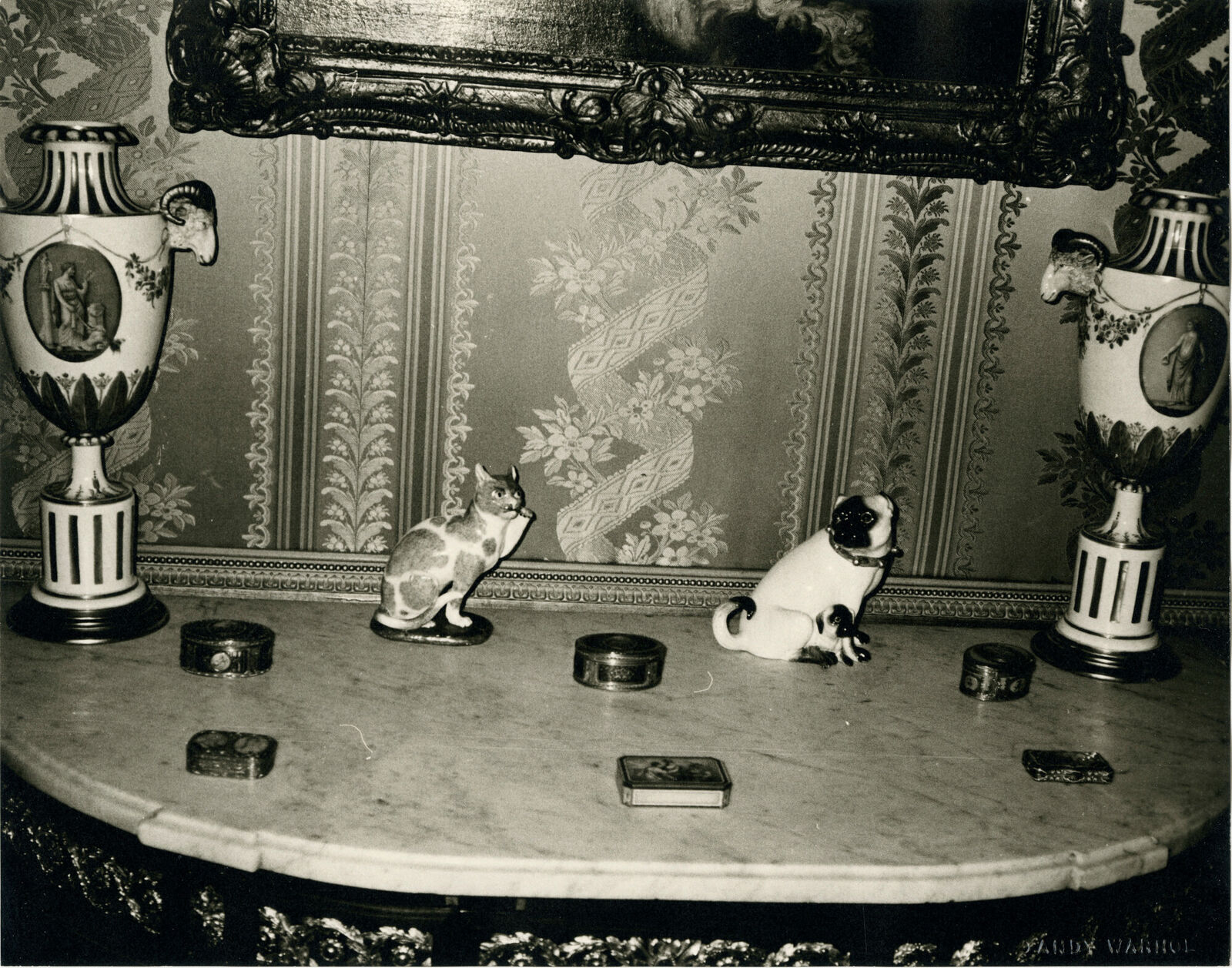 A black and white photo of two cats sitting on a table.