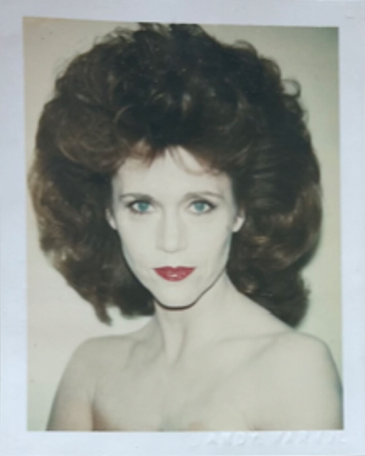 A polaroid photo of a woman with curly hair and red lipstick.