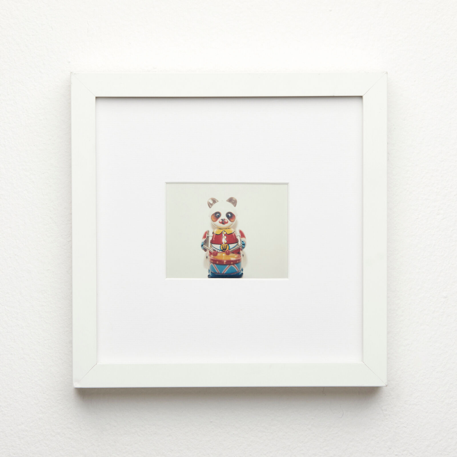 A picture of a panda bear in a white frame on a wall.