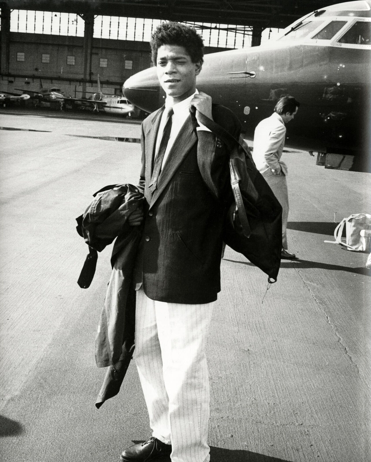 A man in a suit and tie standing in front of an airplane.