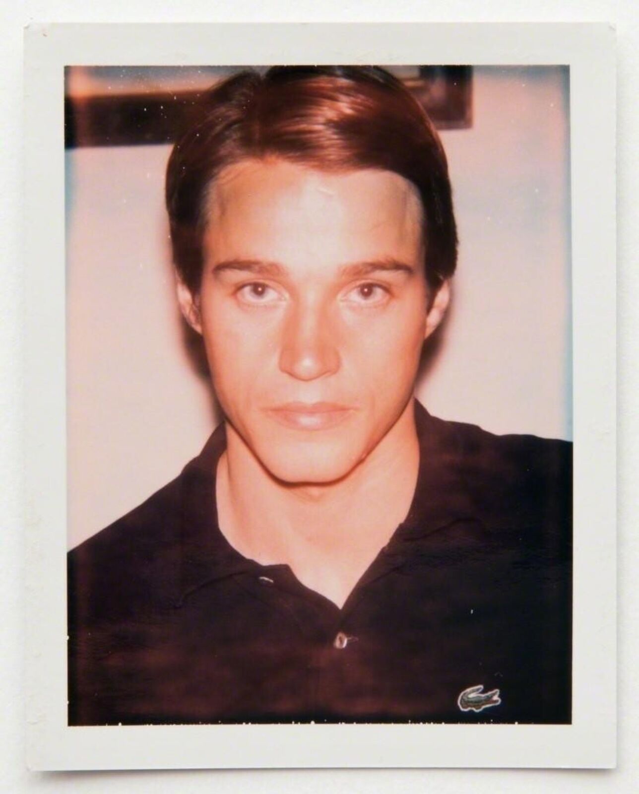 A polaroid photo of a young man in a black shirt.