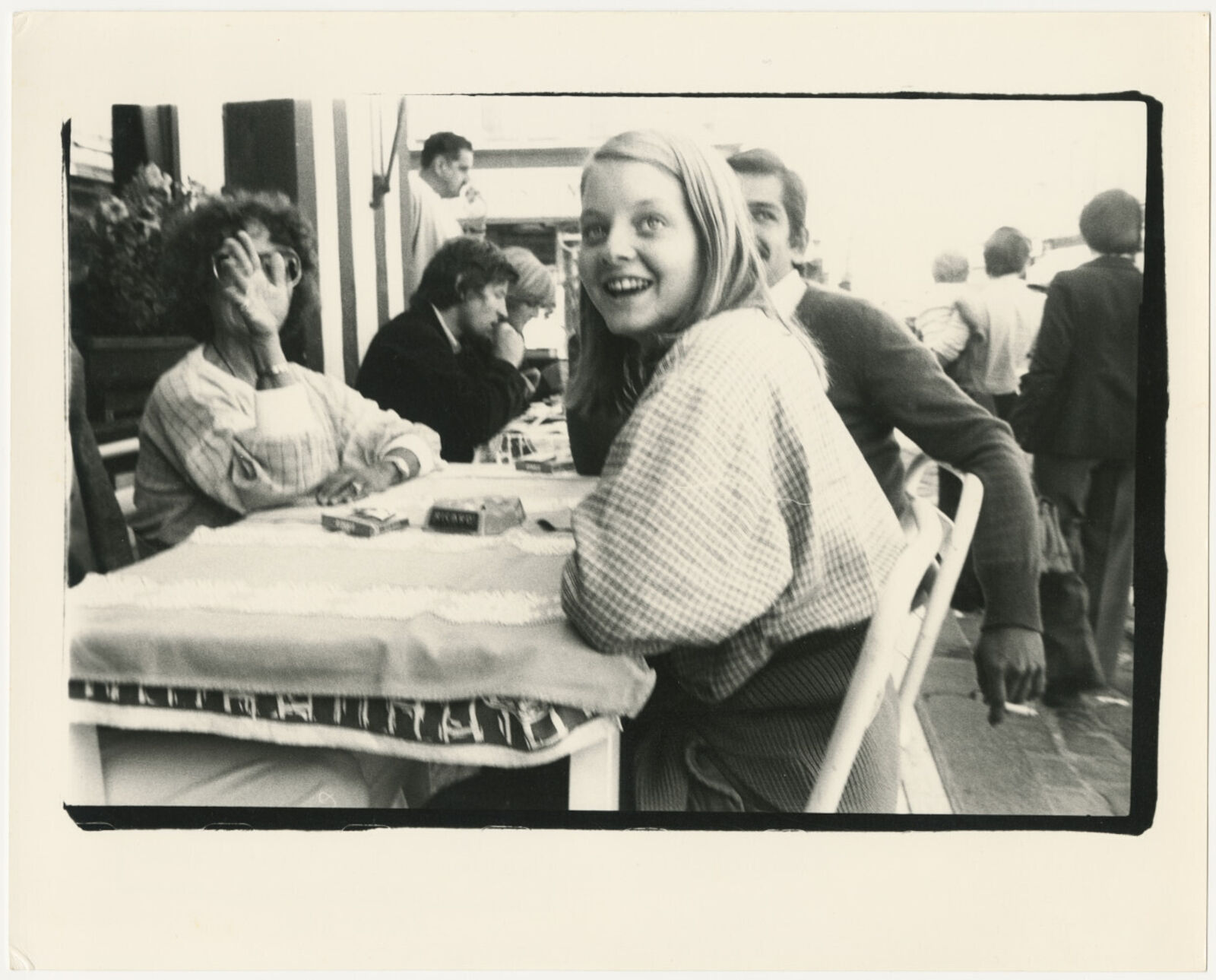 A black and white photo of a woman sitting at a table.