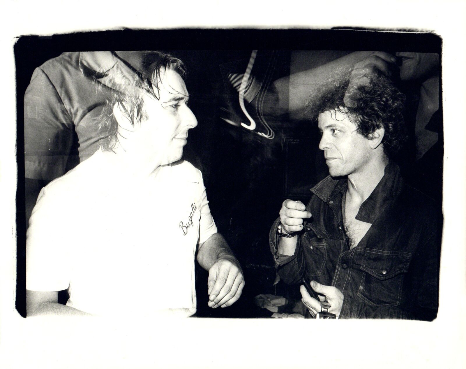 A black and white photo of two men talking.