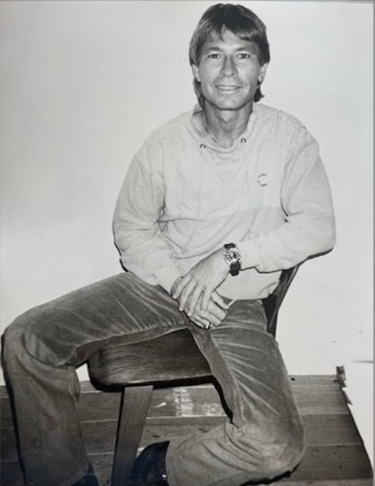 A black and white photo of a man sitting on a chair.
