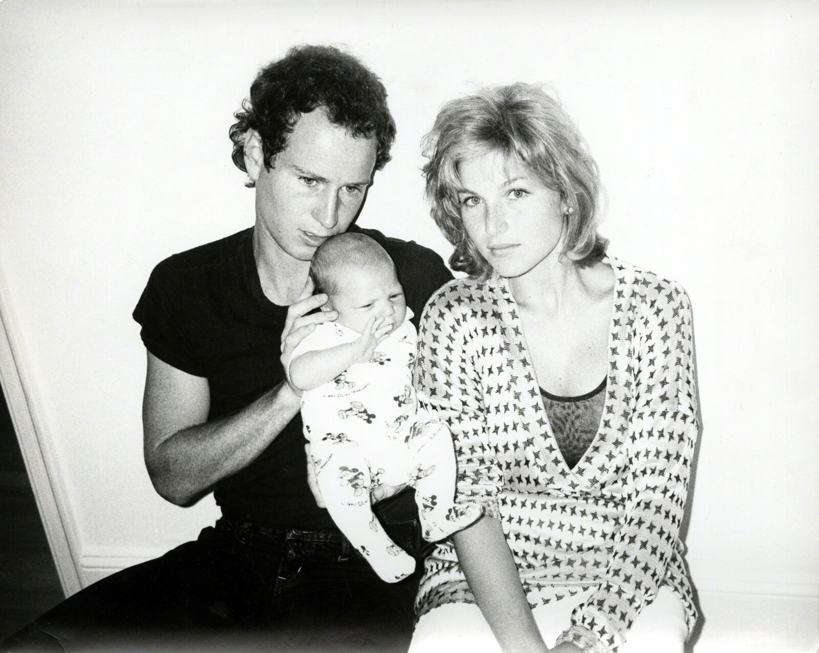 A man and woman holding a baby while sitting next to each other.