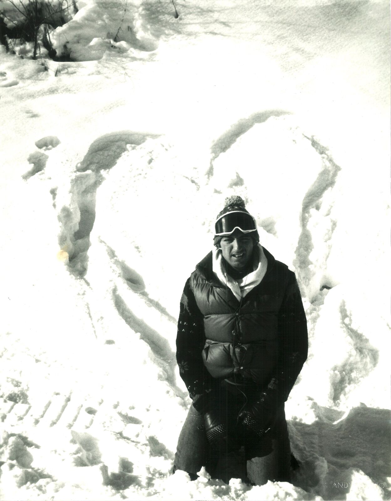 A man standing in the snow next to a snow sculpture.
