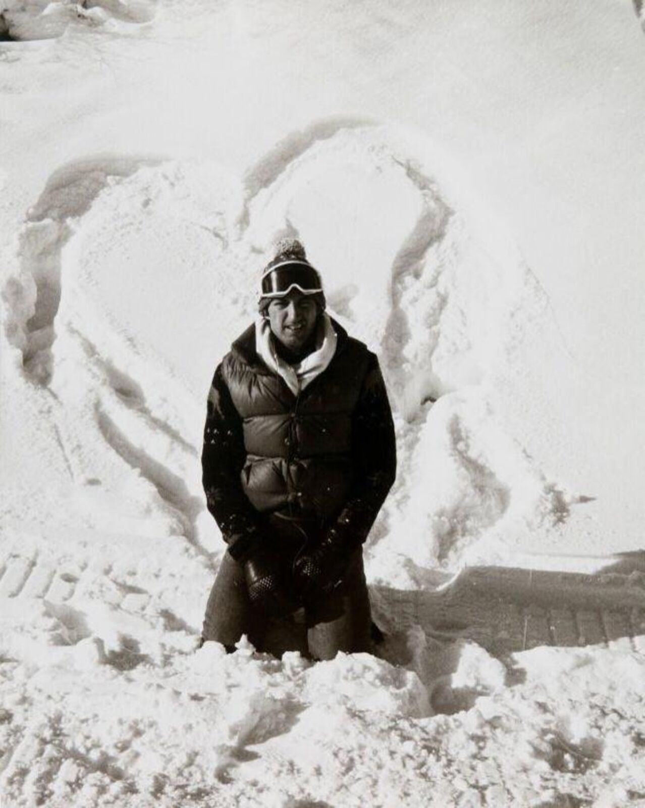 A man standing in the snow next to a snow sculpture.