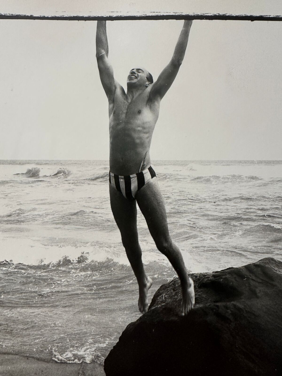 A man standing on top of a rock in the ocean.