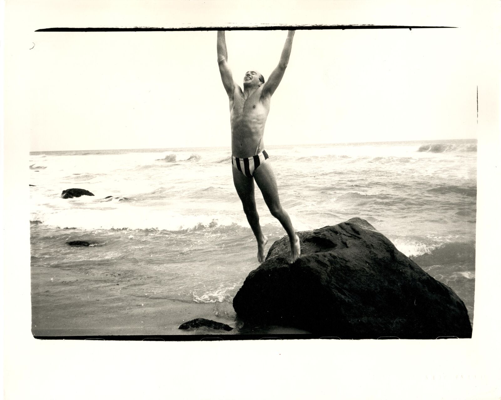 A man standing on top of a rock in the ocean.