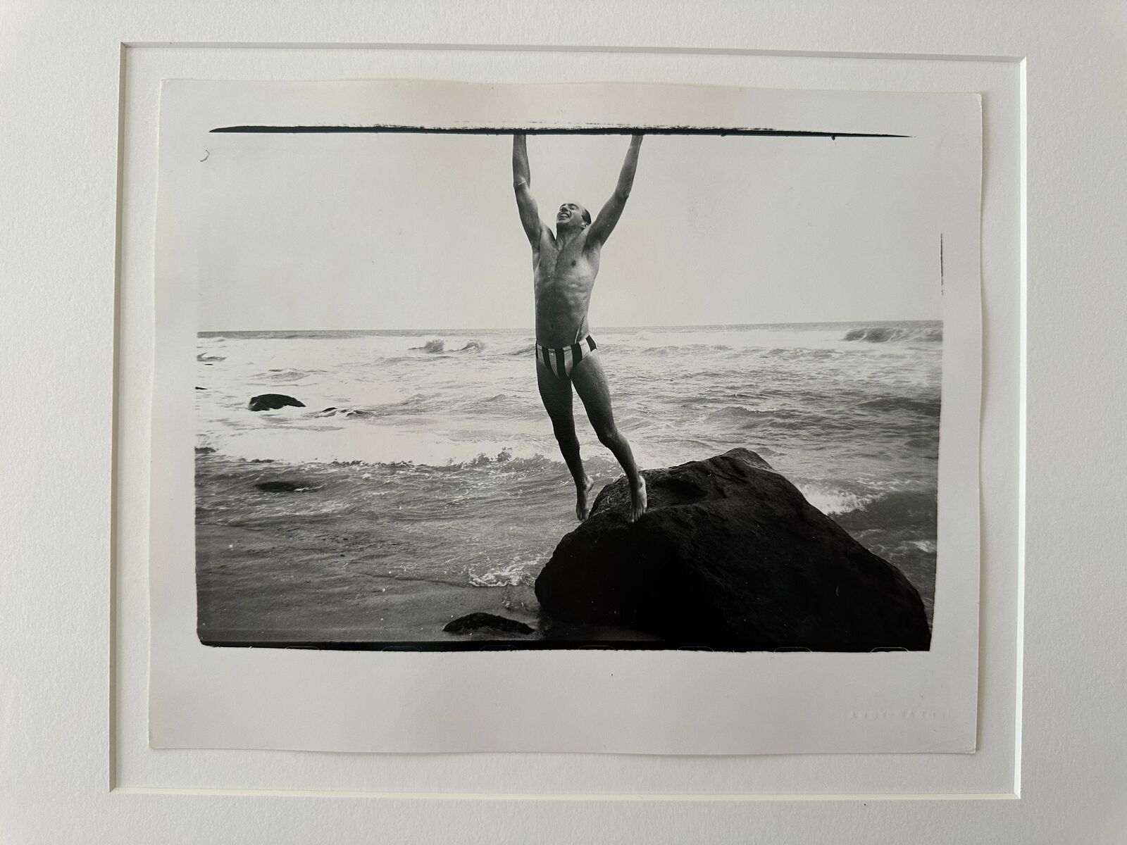 A man standing on top of a rock in the ocean.