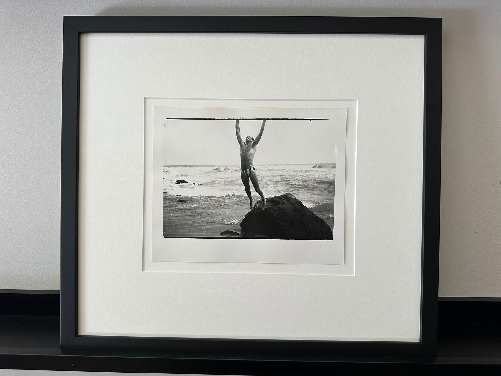 A man standing on top of a rock in the ocean.