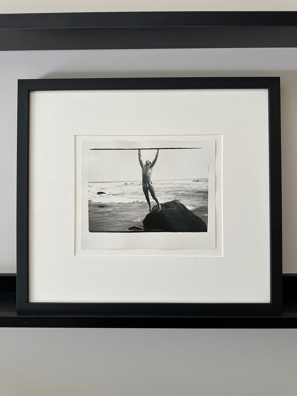 A man standing on top of a rock in the ocean.