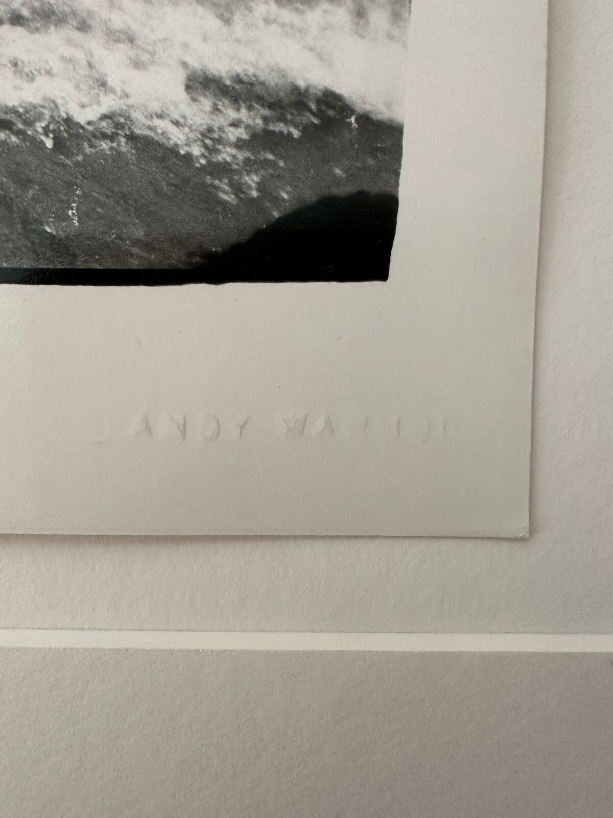 A black and white photo of a person laying on a rock in the ocean.