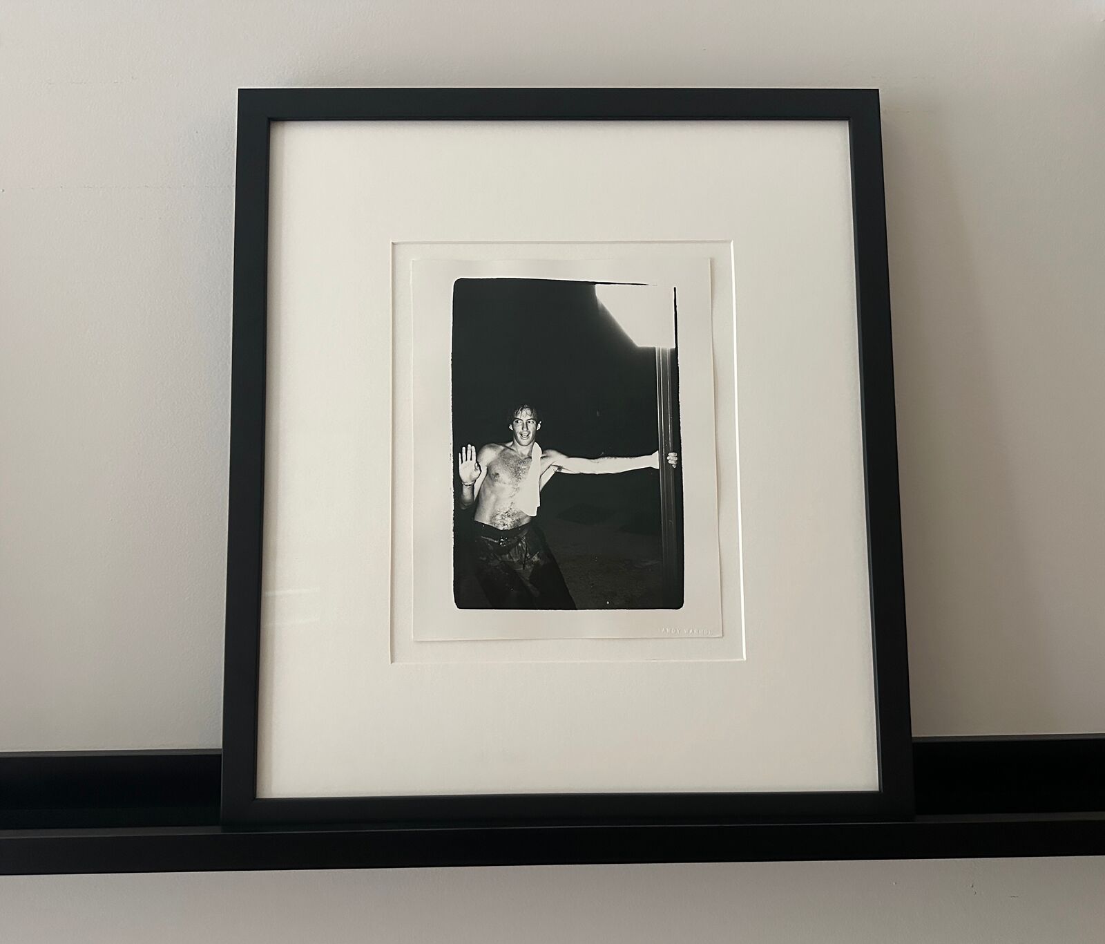 A shirtless man standing in front of a door with his arms outstretched.