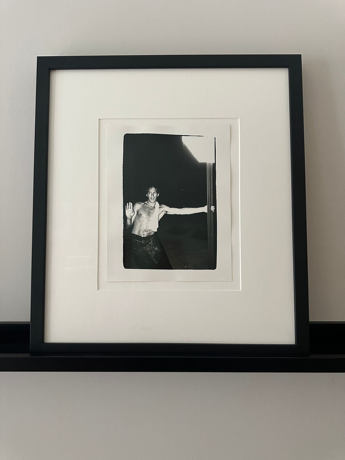 A shirtless man standing in front of a door with his arms outstretched.