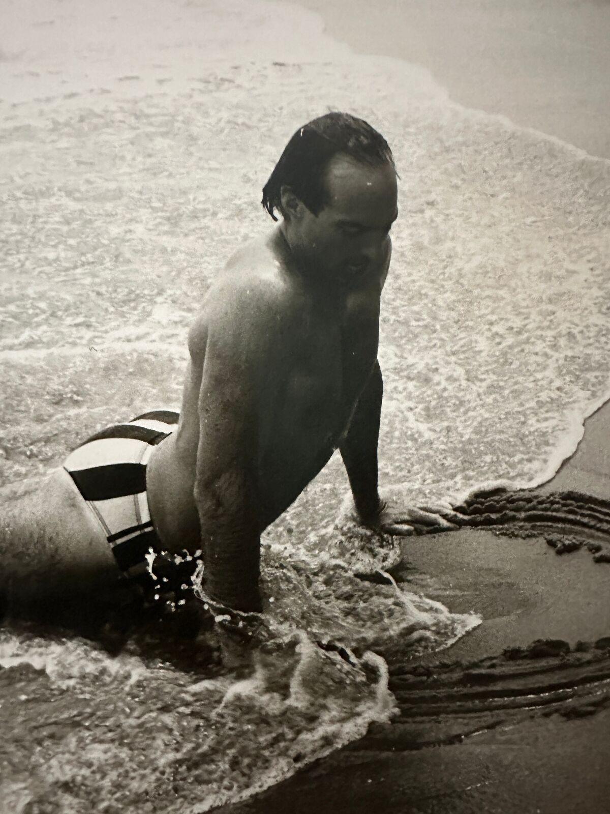 A man in a bathing suit is playing in the water.