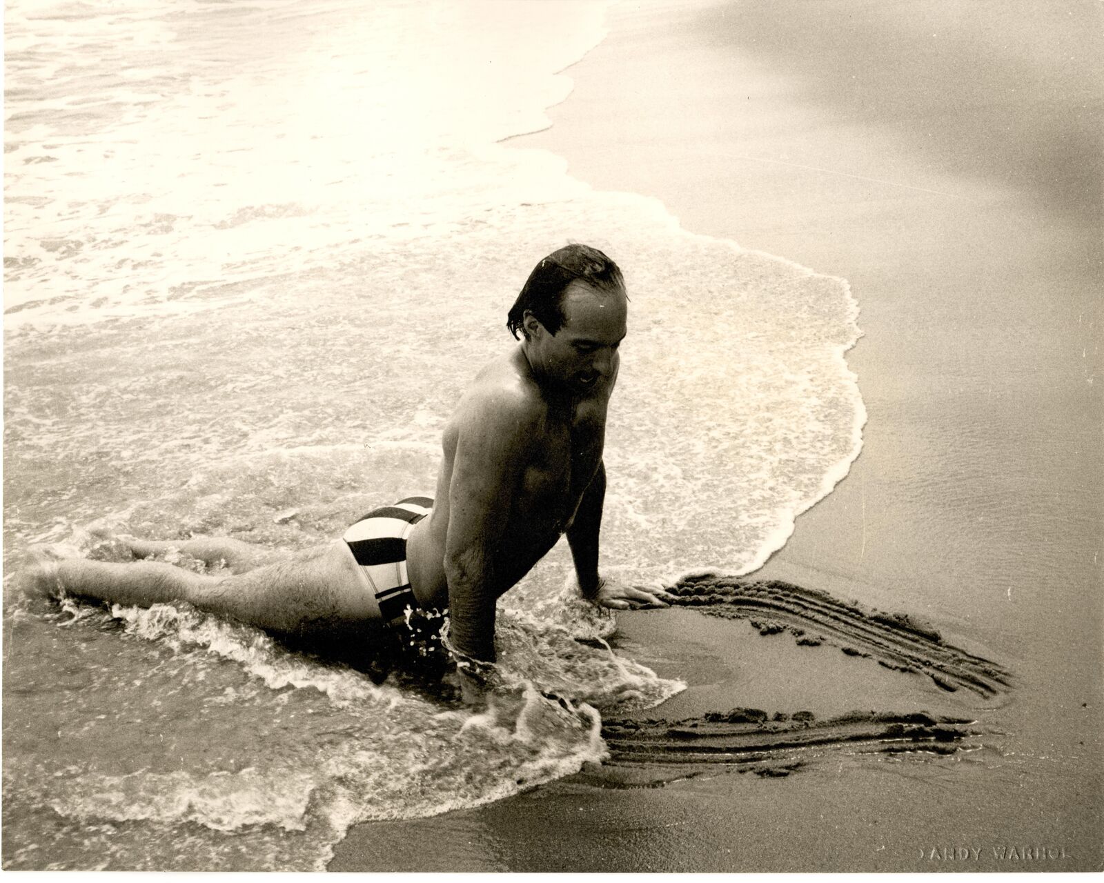 A man in a bathing suit is playing in the water.