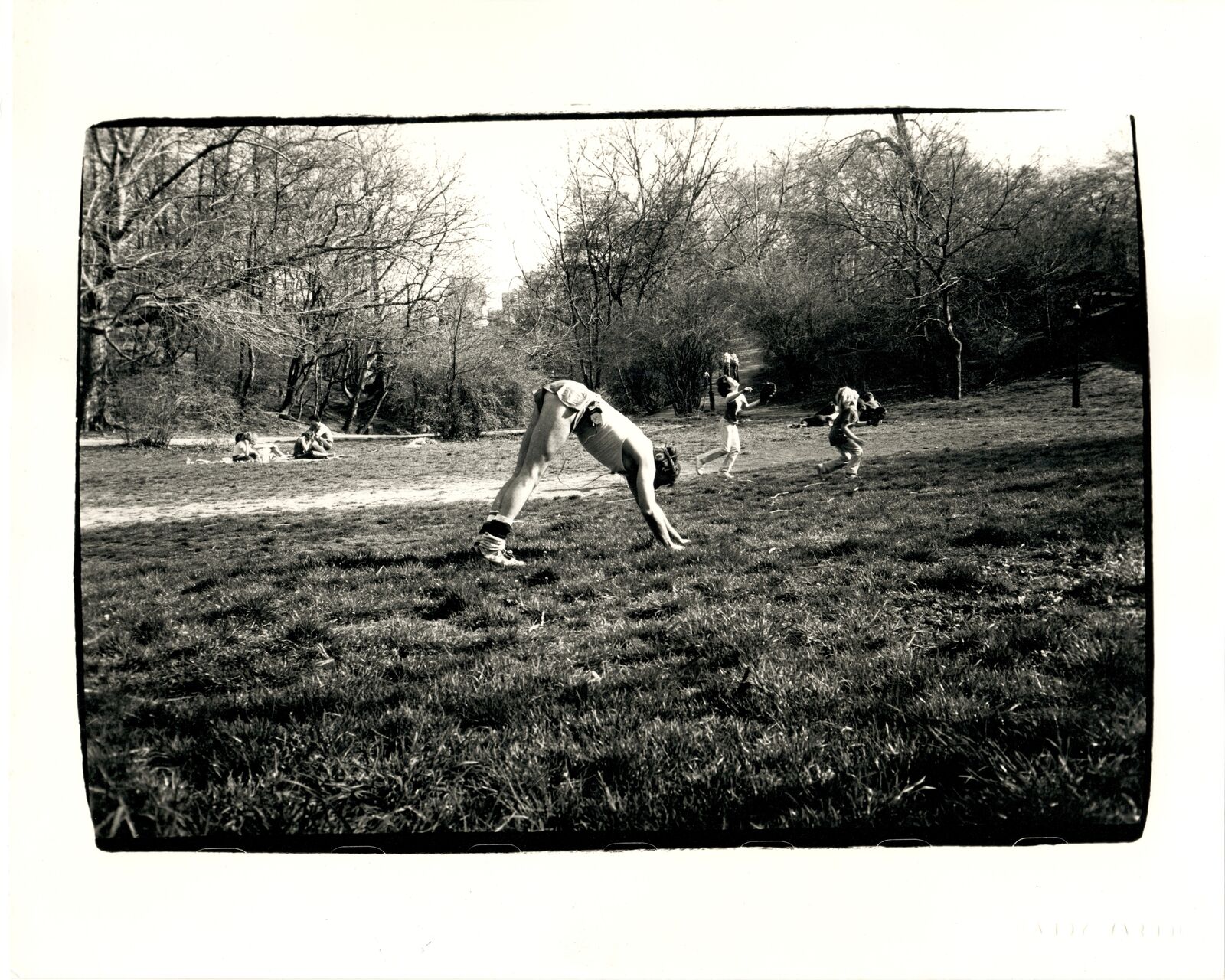 A black and white photo of a person doing a handstand in a park.