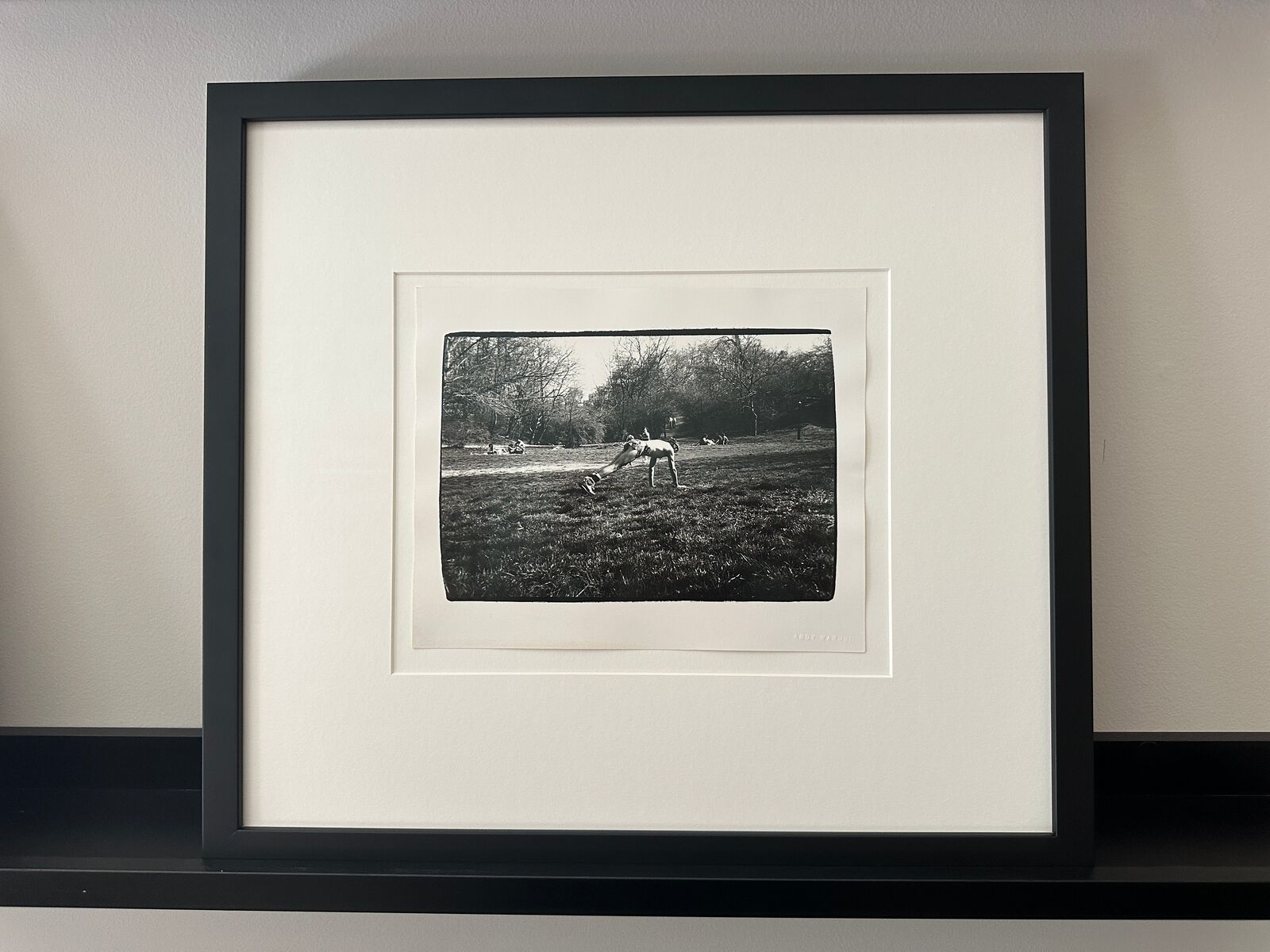 A black and white photo of a man doing a handstand in a park.
