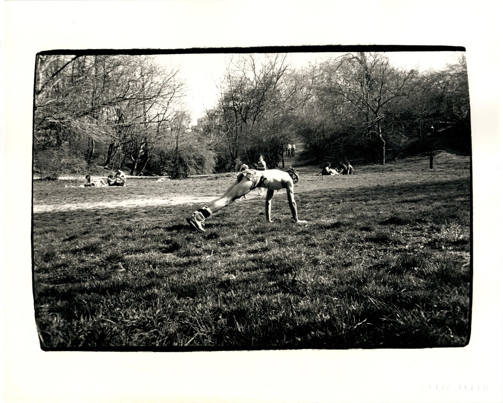 A black and white photo of a man doing a handstand in a park.